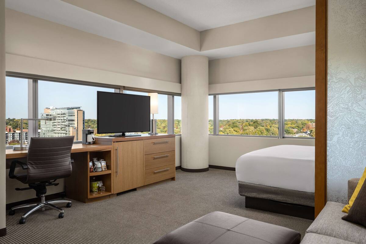 Une chambre d’hôtel avec un grand lit, un bureau avec une télévision et une vue sur la ville.
