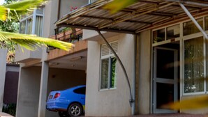 A multi-story residential building with a blue car parked in the driveway. - Nobilis Apartments (Kigali)