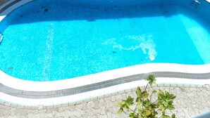 A swimming pool with a tiled edge and a ladder. - Nobilis Apartments (Kigali)
