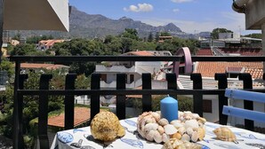 A balcony with a table covered in a tablecloth with fish patterns, a blue candle, and various seashells. - Casa Diana (Giardini Naxos)