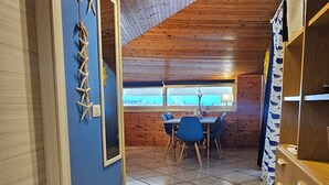 A room with a sloped ceiling, a dining area with chairs, a wooden cabinet, and a wall with decorative shells. - Casa Diana (Giardini Naxos)