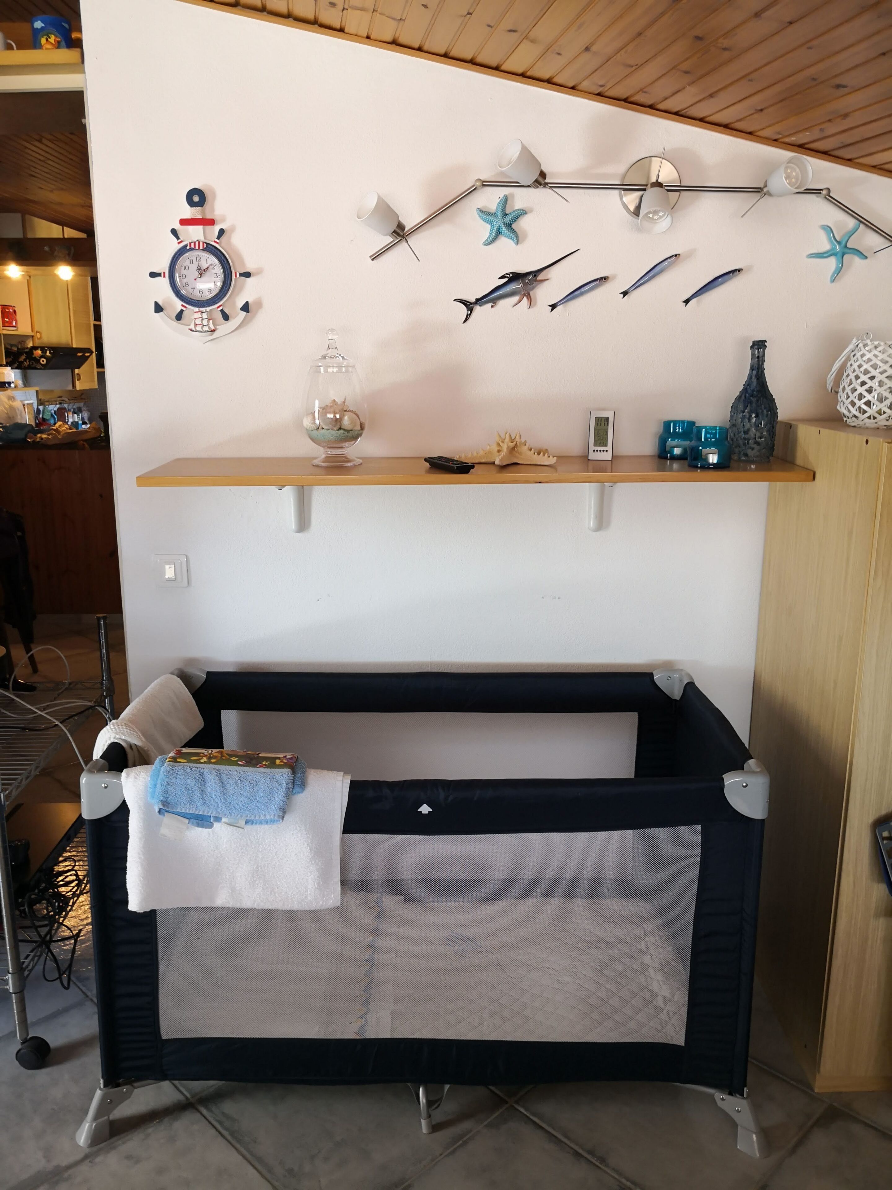 Un berceau pour bébé avec une couverture, une horloge murale et des objets décoratifs, notamment des étoiles de mer et des poissons.