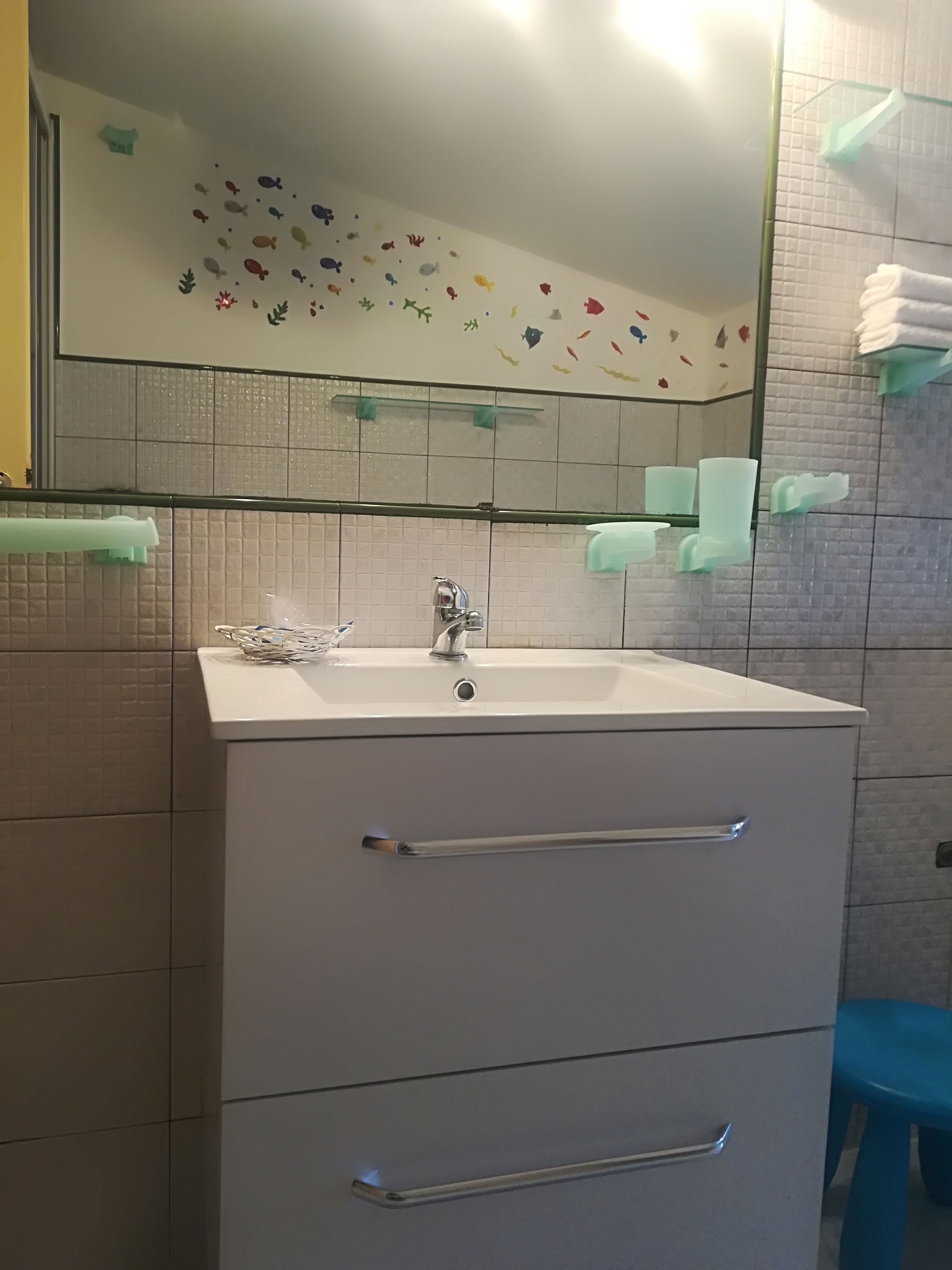 A bathroom with a white sink, a mirror, and a tiled wall.