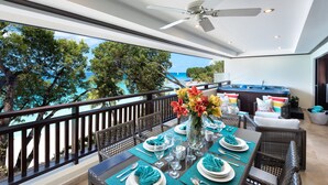 A dining area with a view of the ocean, a ceiling fan, and a hot tub. - Coral Cove 11 by Altman (Paynes Bay)