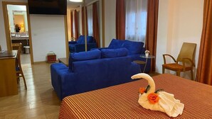 A hotel room with a large bed, a blue sofa, a desk, and a TV. - Hotel Las Tablas (Daimiel)