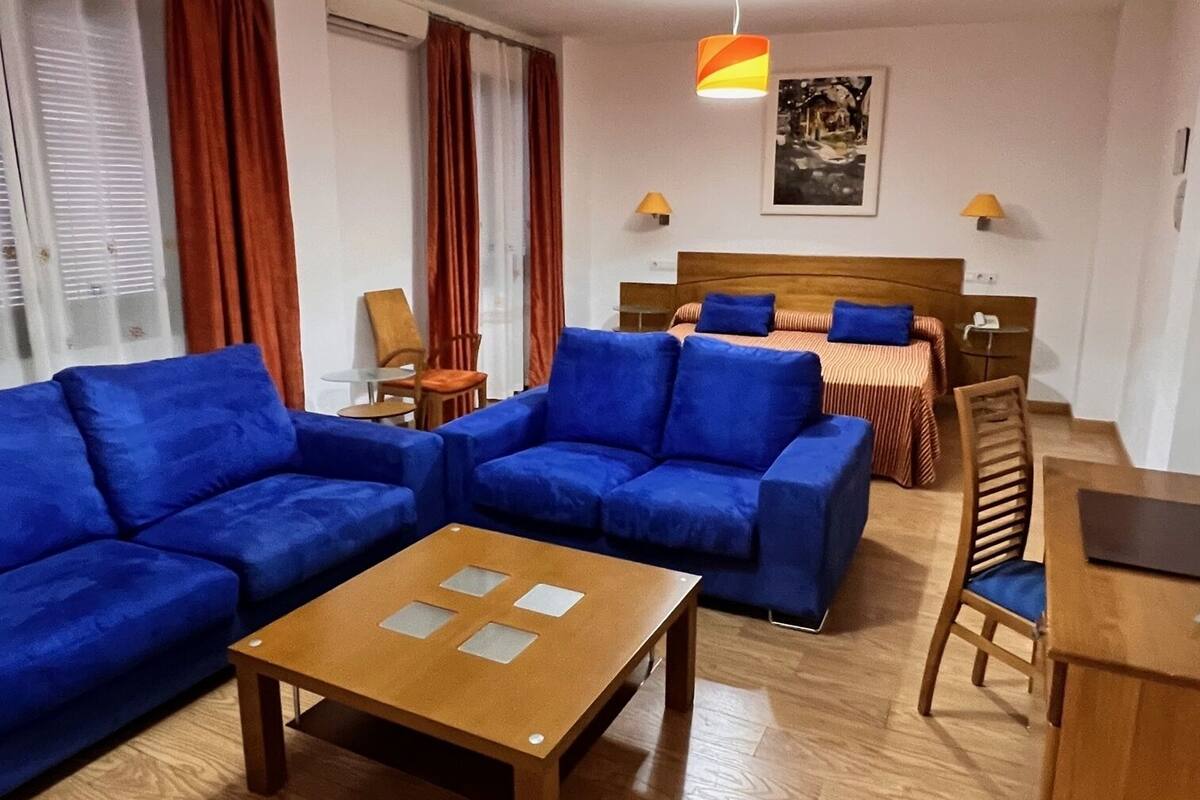 A modern living room with blue sofas, a wooden coffee table, and orange pendant lights.