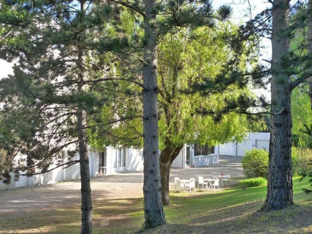 A courtyard with trees, a white building, and outdoor seating.