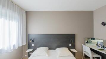 A modern hotel room with a large bed, a desk, and a chair.