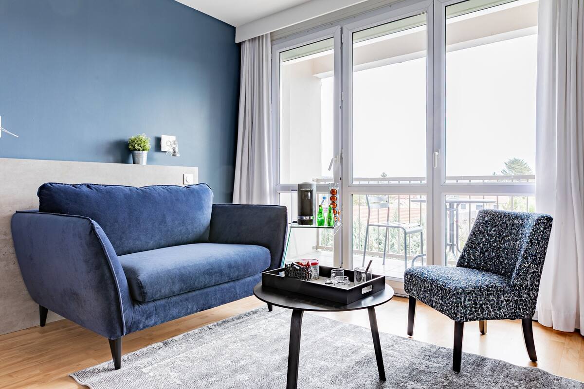 A modern living room with a blue sofa, a patterned armchair, and a coffee table.