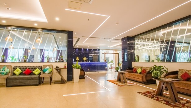 Um lobby moderno com balcão de recepção, áreas de estar e uma grande janela.