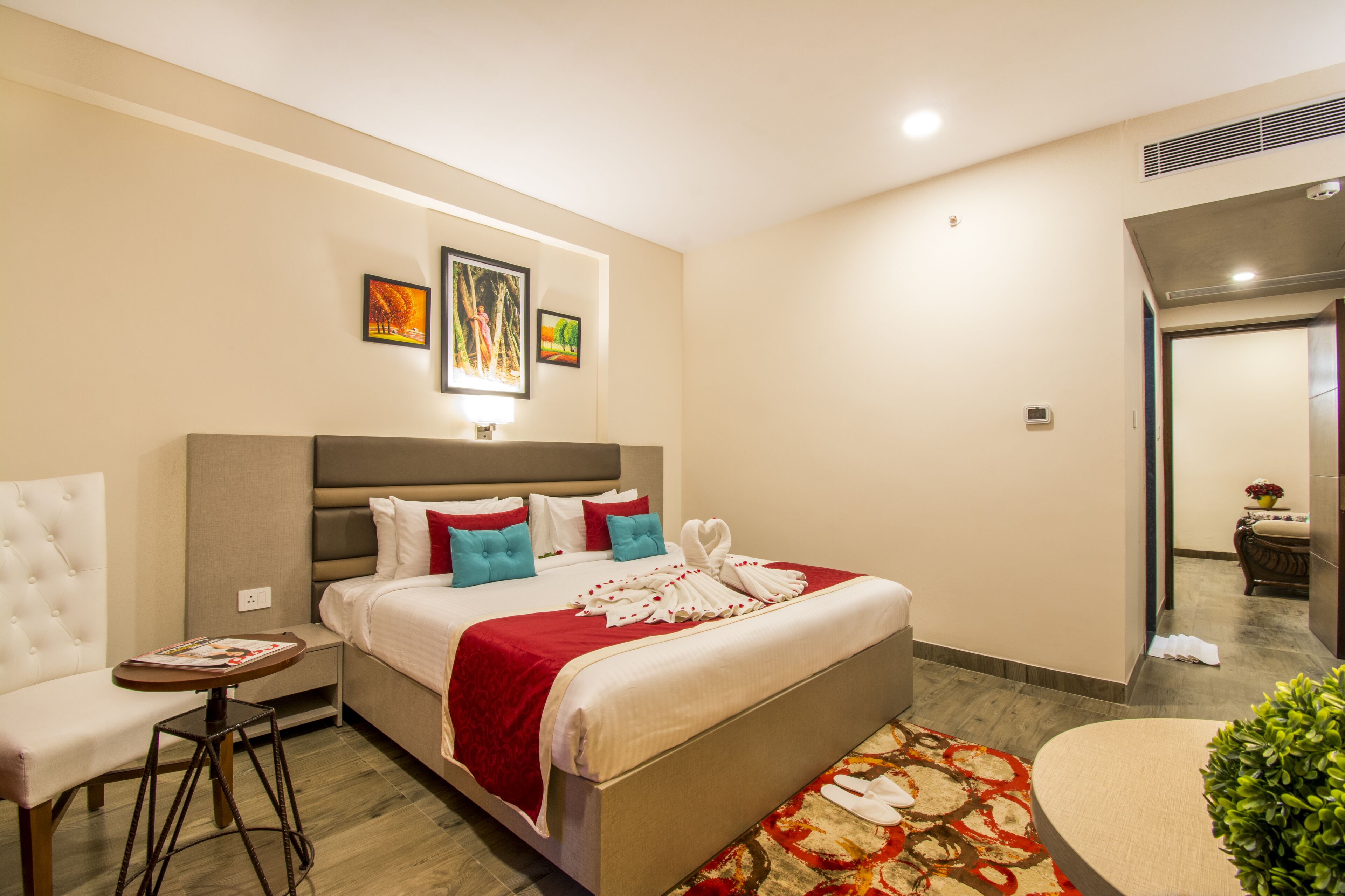 A hotel room with a bed, a chair, a small table, and a decorative plant.