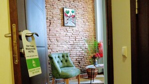 A hotel room with a green tufted chair, a brick wall, and a painting. - Old Town Mtatsminda (Tbilisi)