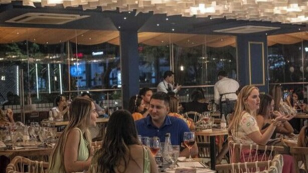 A restaurant with wooden chairs and tables, large windows, and hanging pendant lights. - Hotel Estancia Chipichape Cali (Cali)