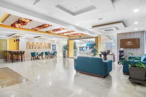 A modern hotel lobby with a reception desk, seating area, and a TV screen displaying the hotel name. - Hotel Estancia Chipichape Cali (Cali)