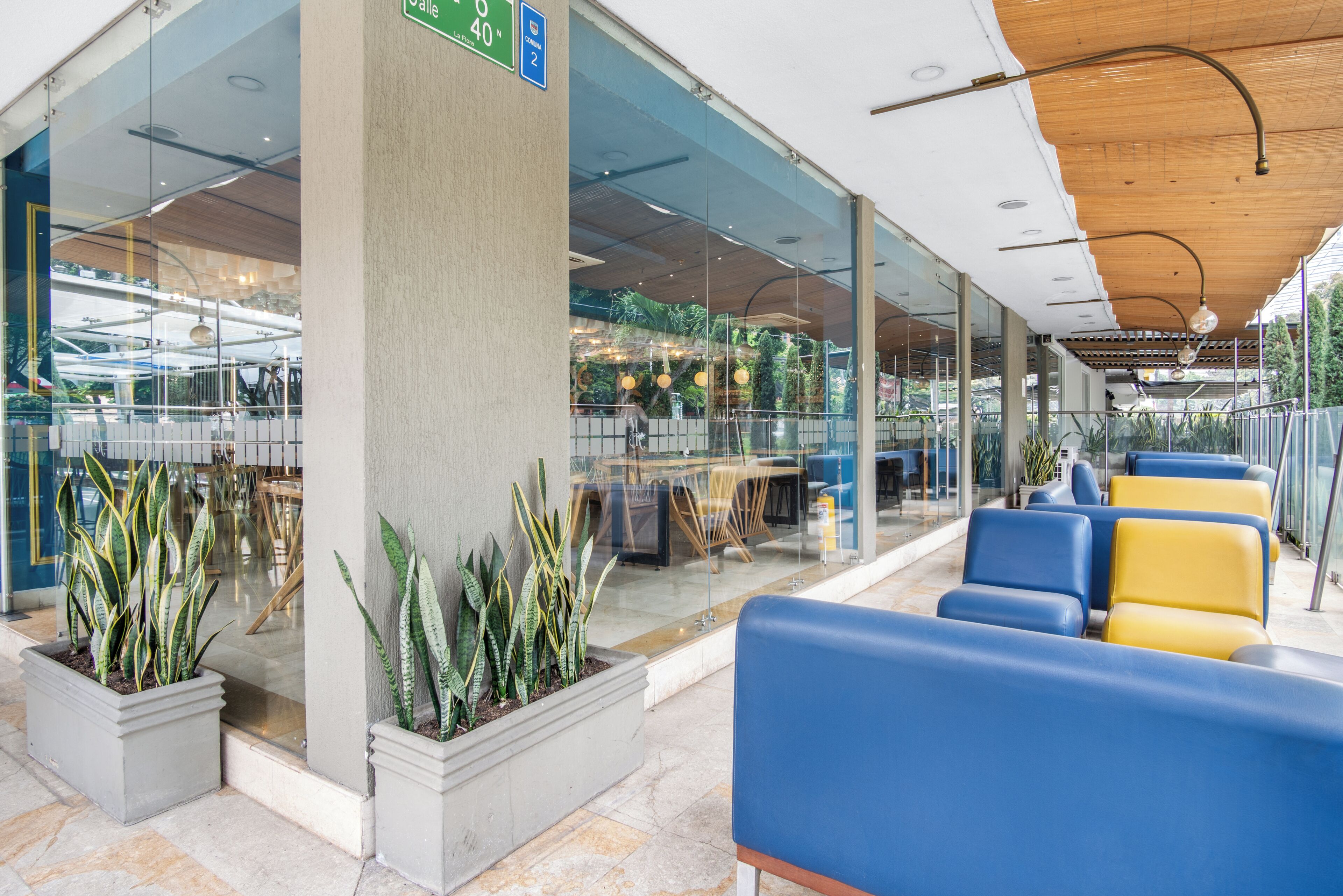 A modern indoor area with seating, glass walls, and potted plants.