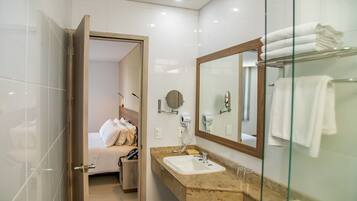 Un baño moderno con cabina de ducha de vidrio, un lavabo con encimera de mármol y un espejo grande.