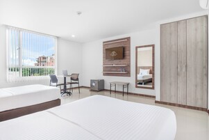 Habitación de hotel con dos camas, un escritorio, un televisor, un espejo y un armario.