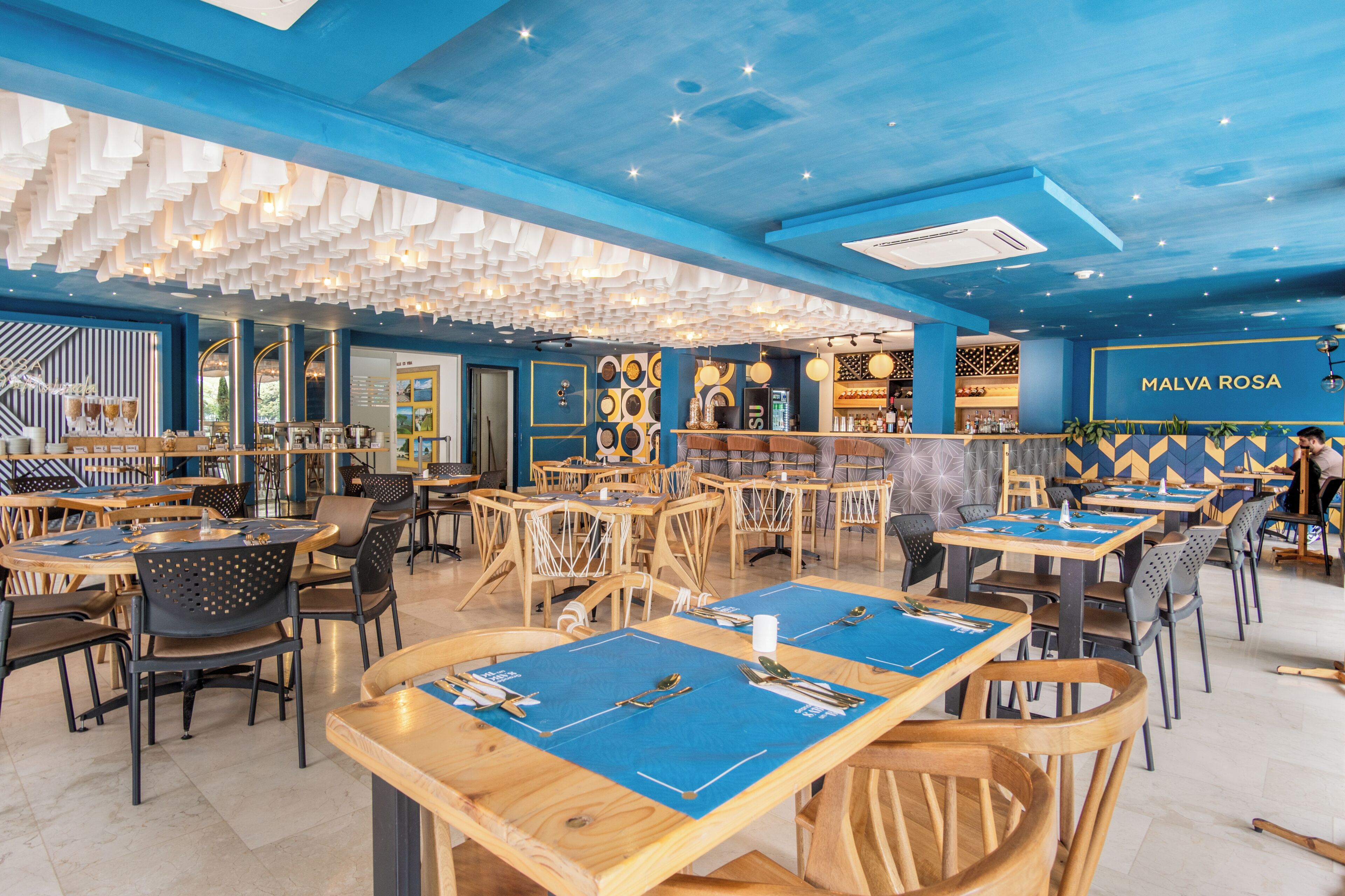 A restaurant interior with multiple tables, chairs, and a bar area.