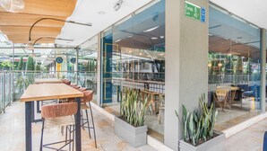A modern indoor space with a wooden ceiling, glass walls, and a seating area with tables and chairs. - Hotel Estancia Chipichape Cali (Cali)