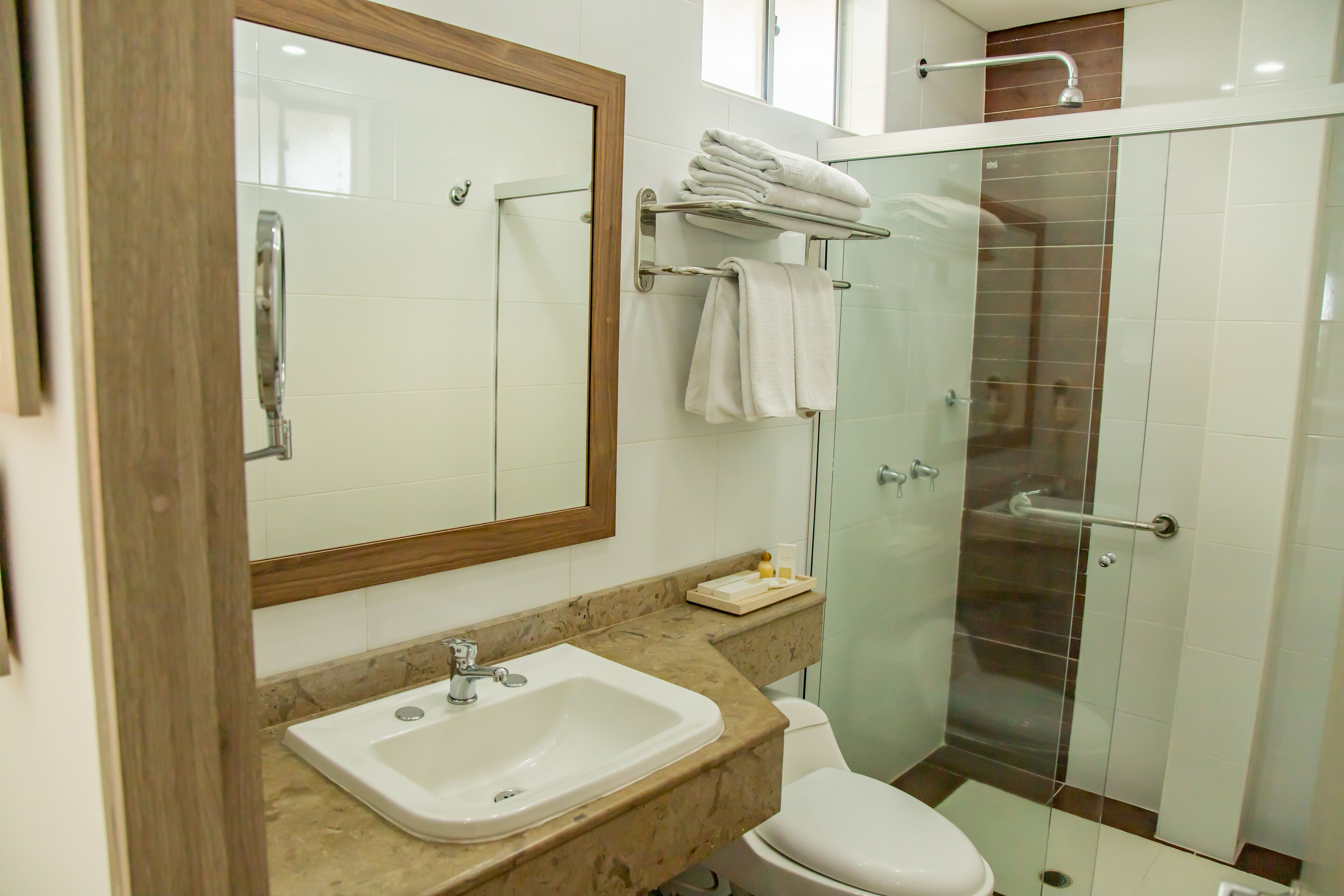 Ein Badezimmer mit Waschbecken, Spiegel, Toilette und Duschkabine.