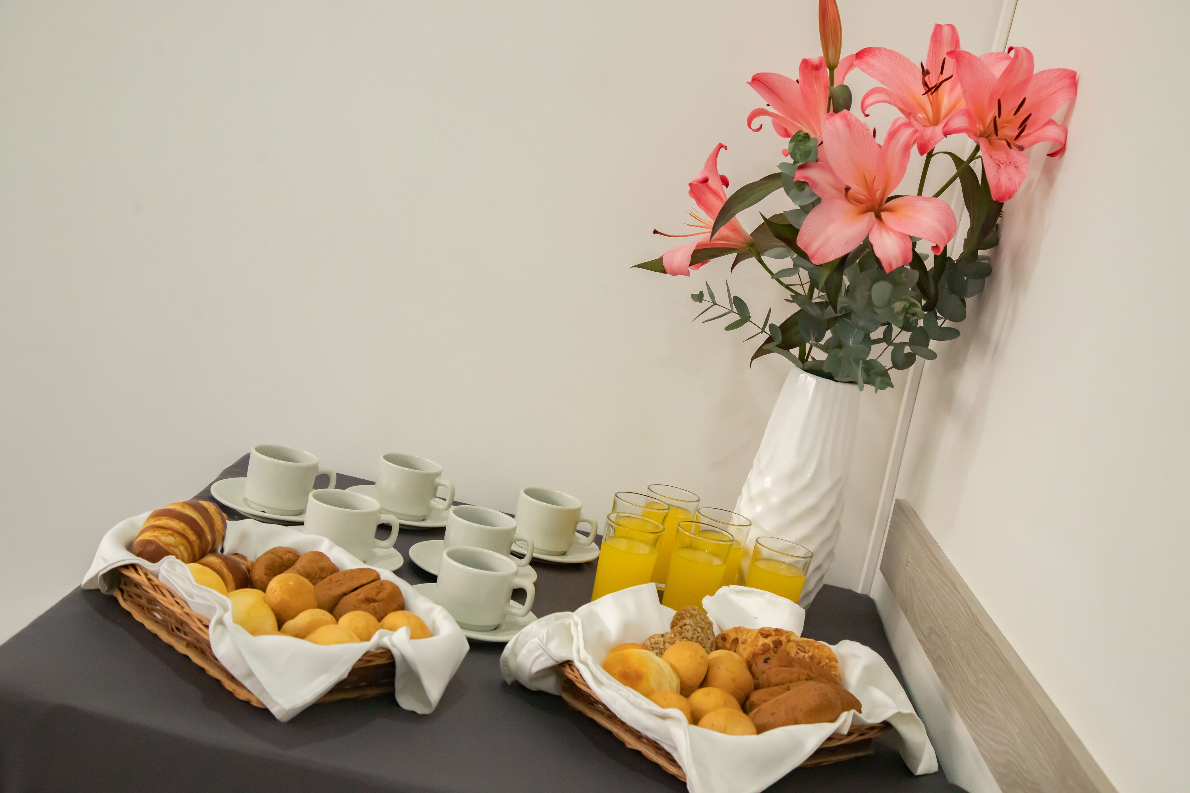 Egy asztalon elrendezve a reggeli: croissant-ok, muffinok és gyümölcslé.