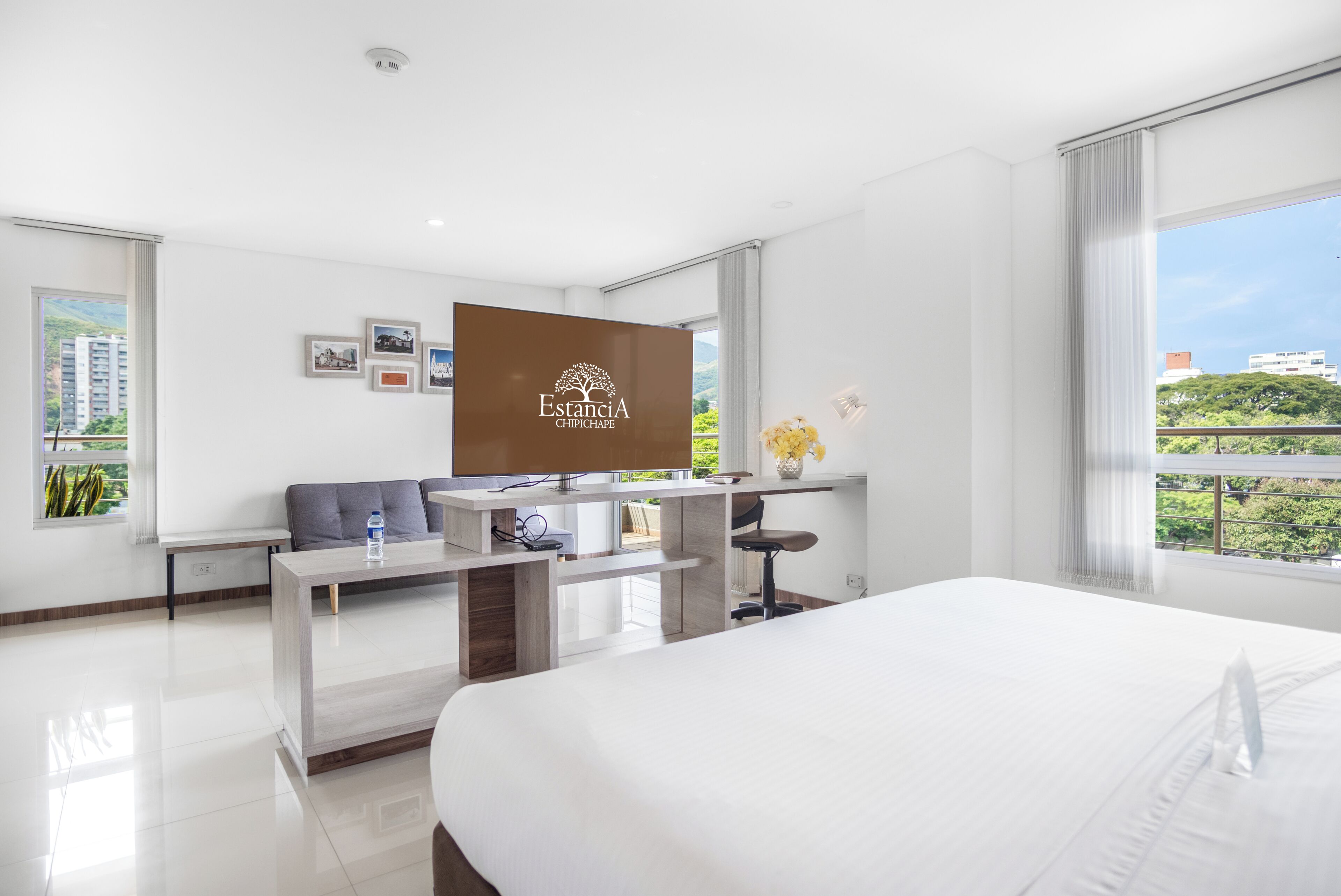 Una habitación de hotel moderna con cama, escritorio y ventana grande.