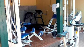 A gym with exercise equipment, a treadmill, and a wall-mounted fan.