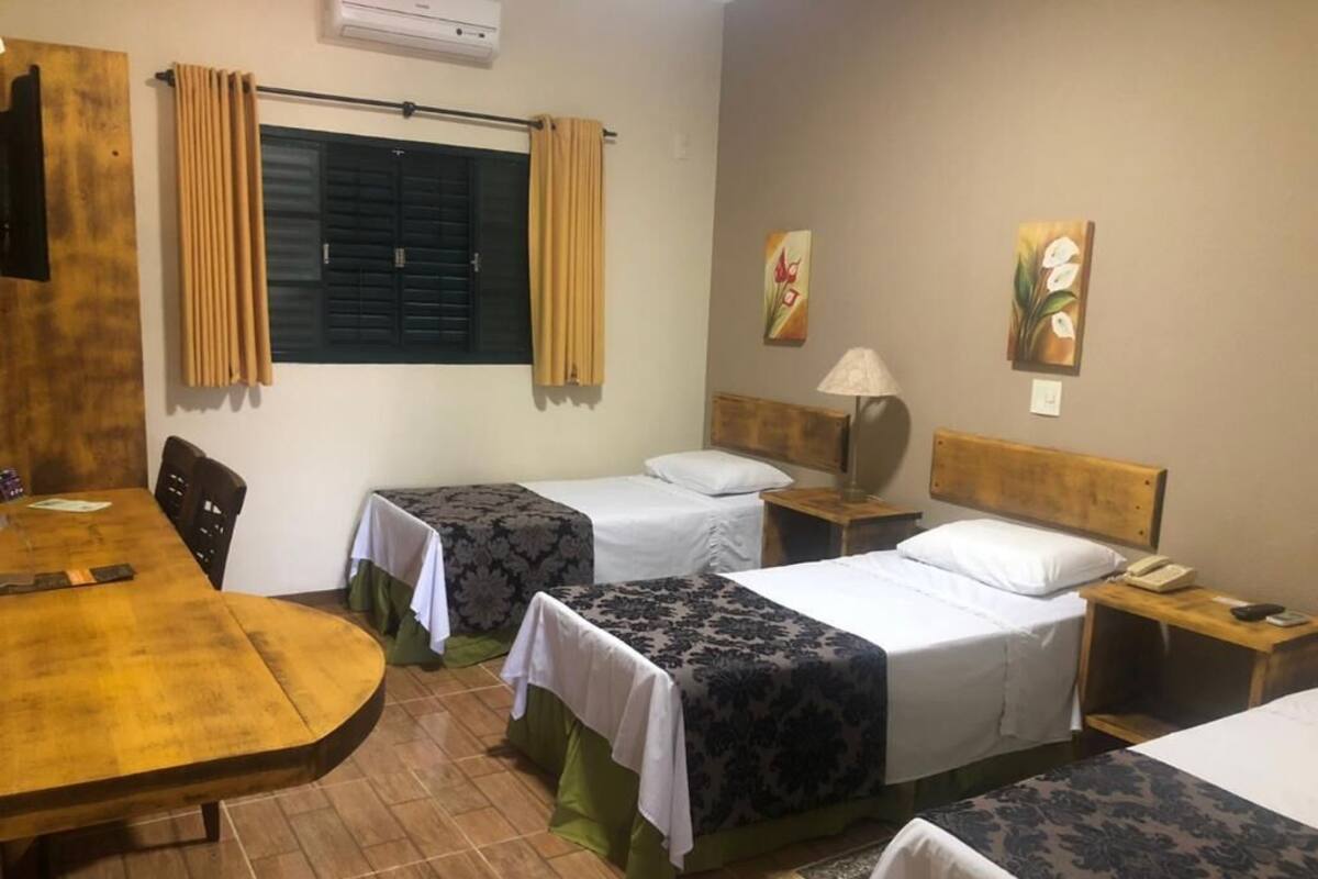 Ein Hotelzimmer mit zwei Einzelbetten, einem Holztisch, einem Stuhl, einem Schreibtisch und einer Lampe.