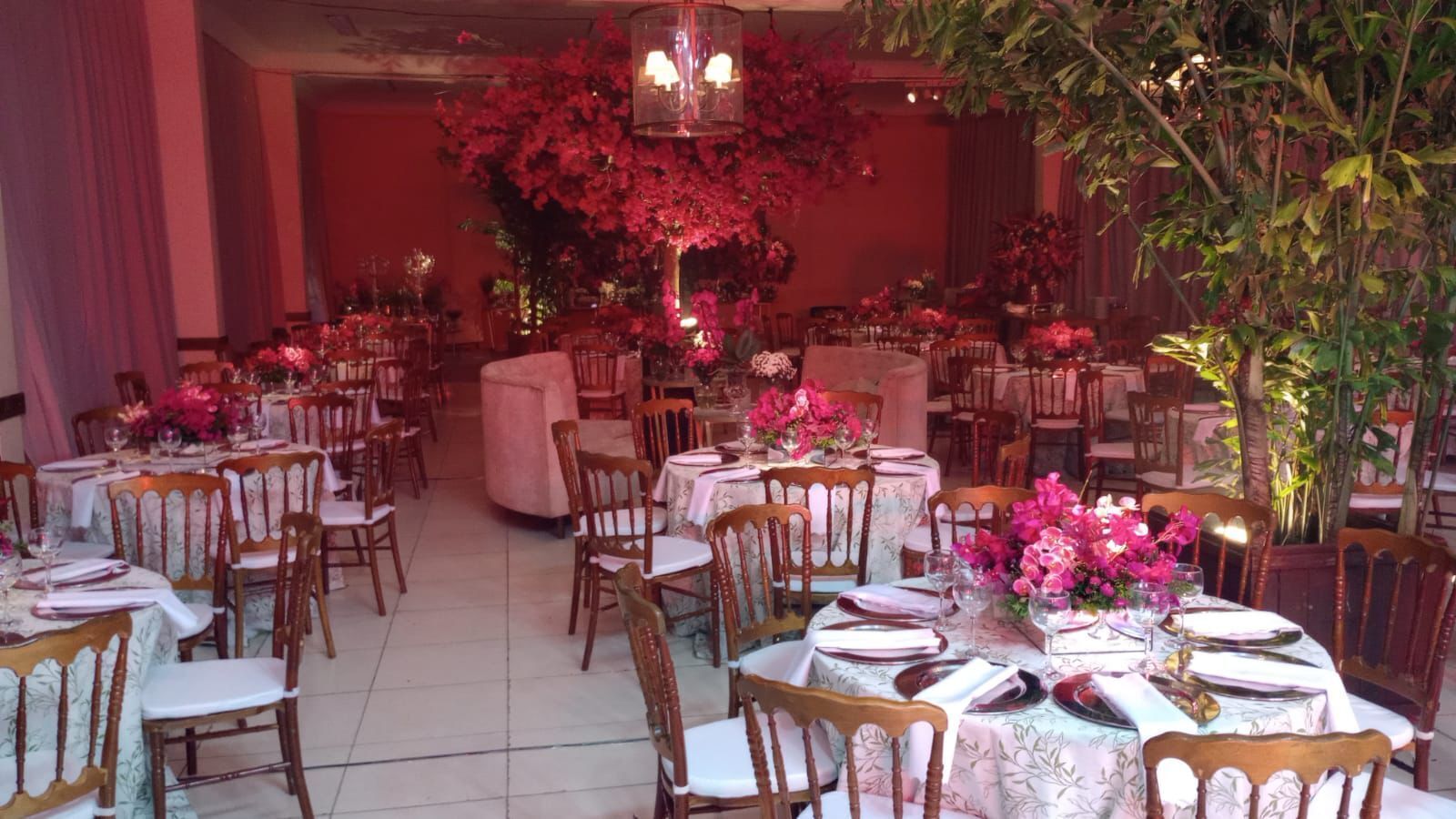 Un salón de banquetes con mesas redondas, sillas y centros de mesa con flores.