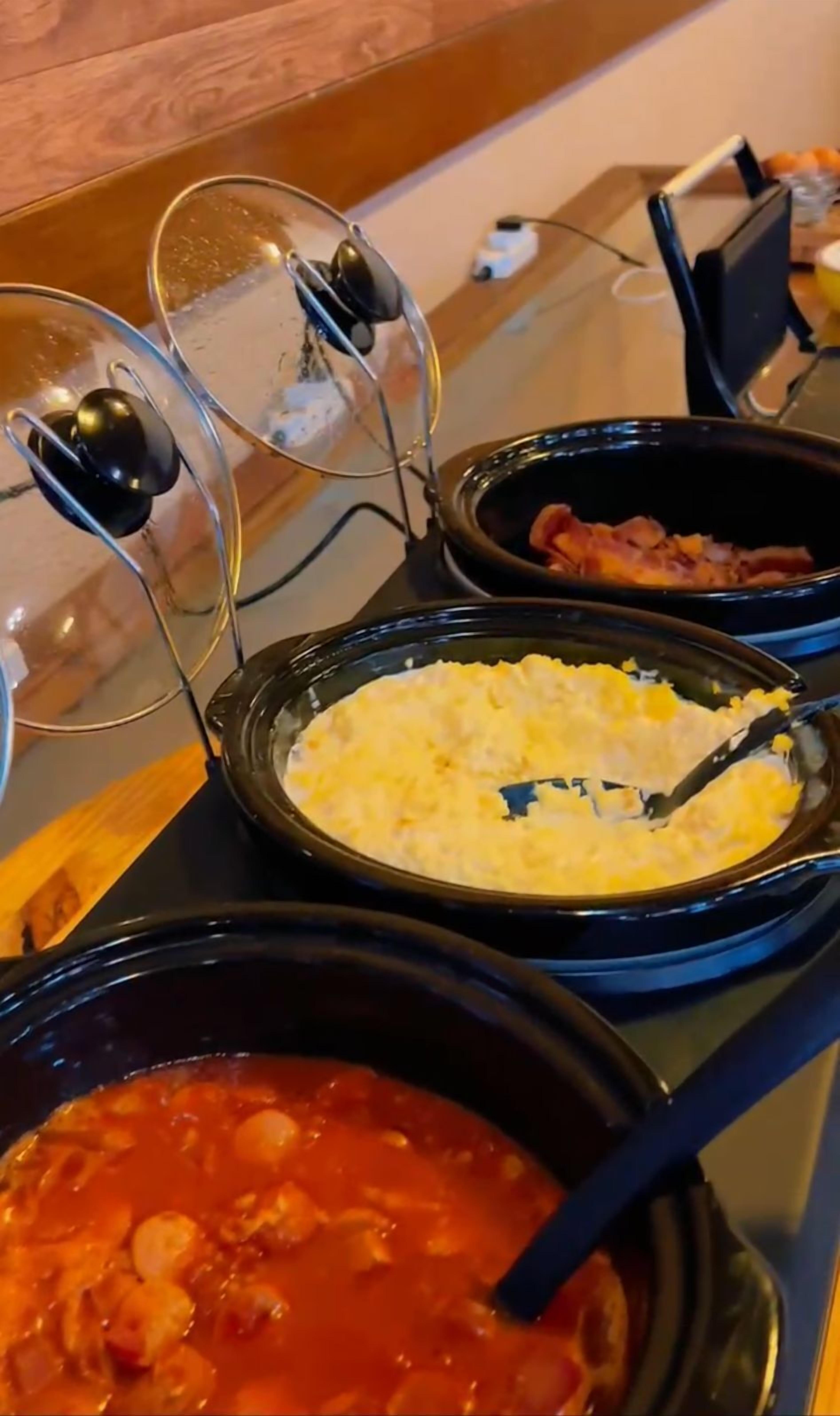 Una mesa con tres recipientes de comida: uno con sopa roja, otro con un plato amarillo y un tercero con salsa oscura.
