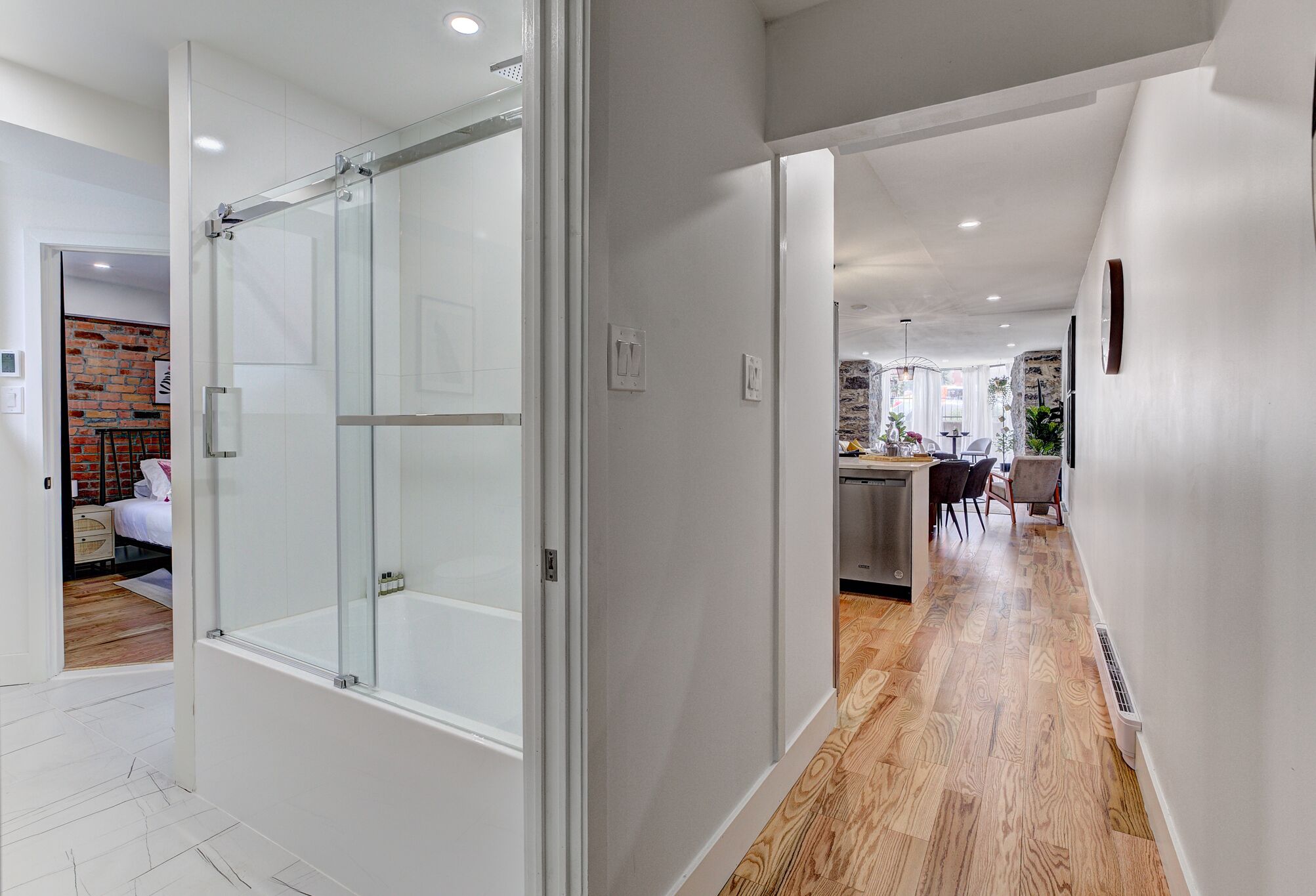 A modern interior with a glass shower, a kitchen area, and a dining space.