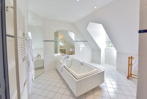 Une salle de bain moderne avec une baignoire sur pieds, un grand miroir et une fenêtre de toit.