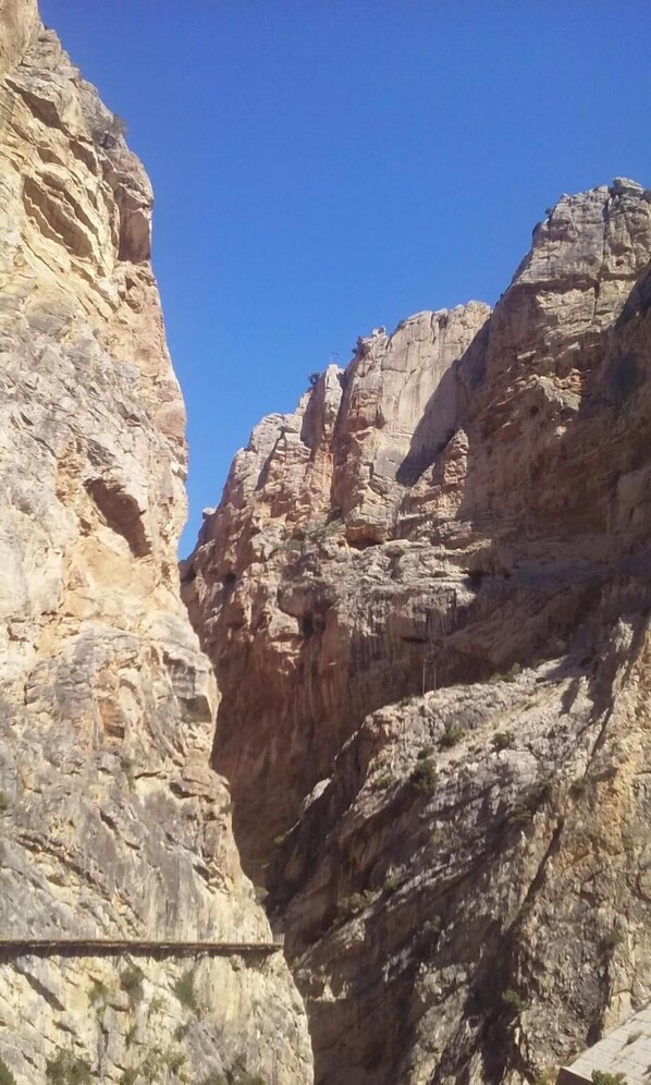 A narrow canyon with steep rock walls and a clear blue sky.
