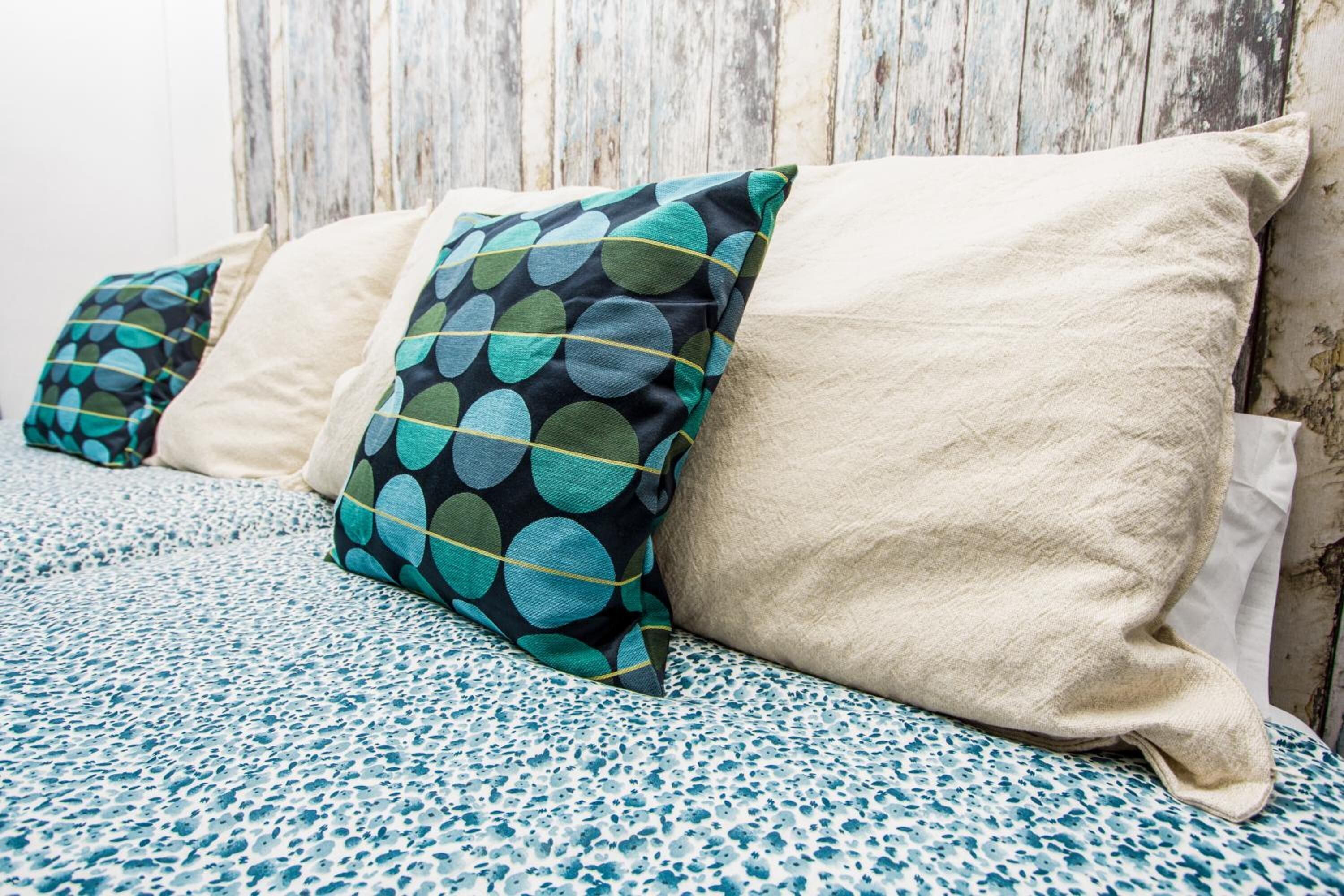 A bed with a blue and white speckled bedspread and pillows with a polka dot pattern.