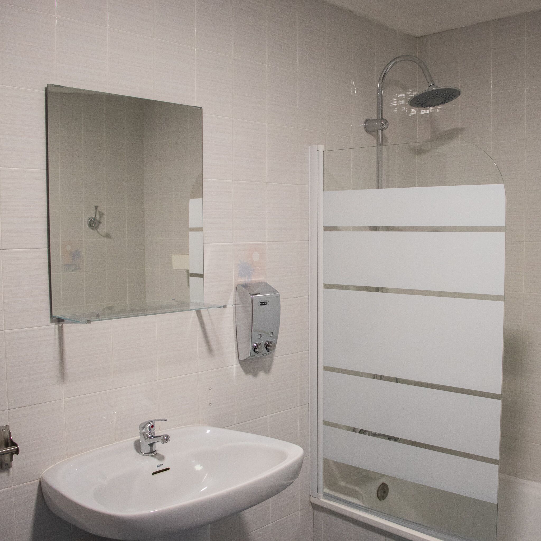 Un baño con lavamanos, espejo y ducha.