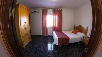 A bedroom with a bed, a wooden wardrobe, a nightstand, and a window with curtains.