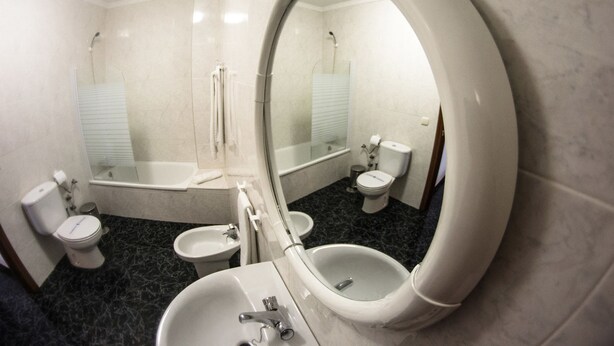 Un baño con inodoro, bidé, lavabo y un espejo grande.