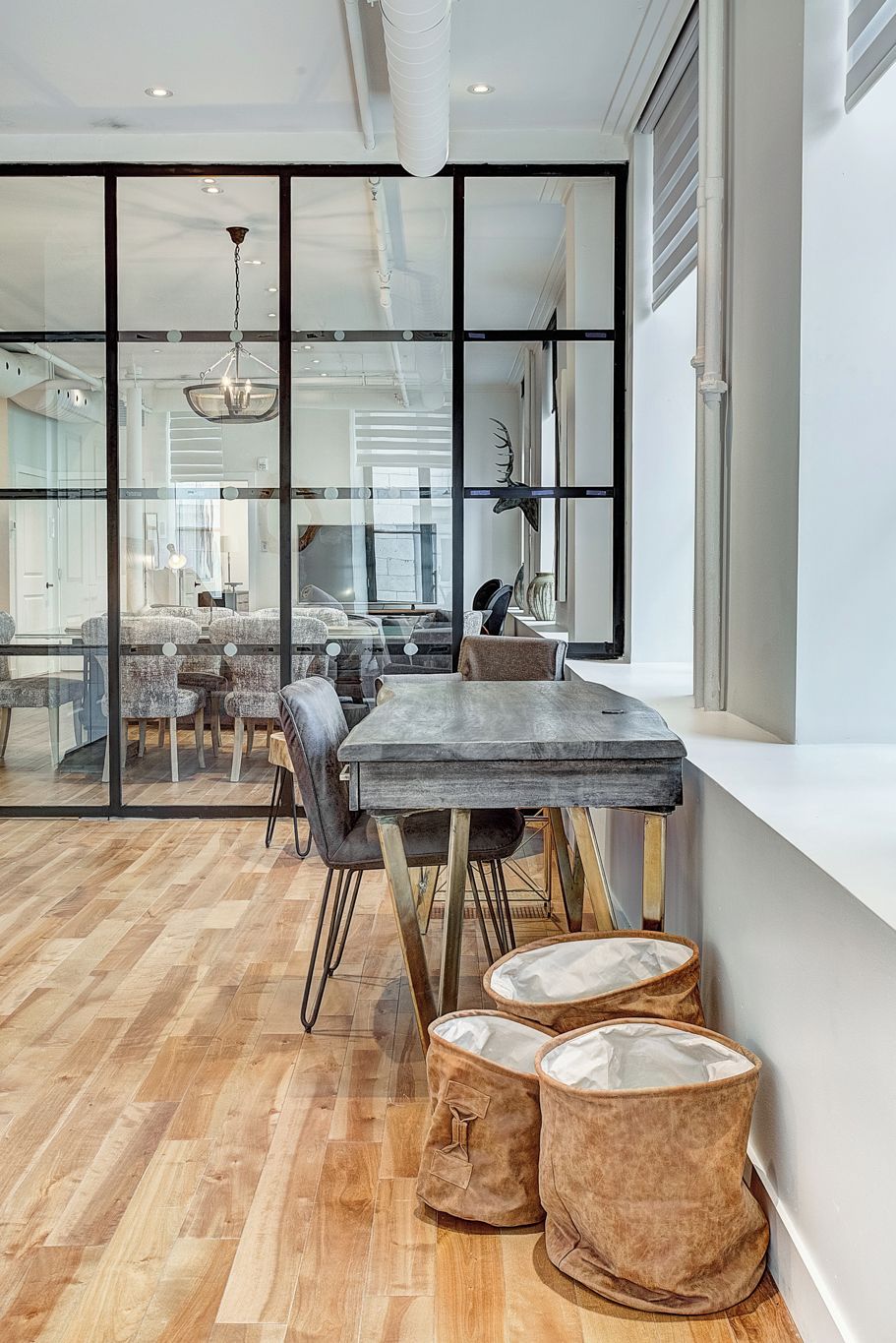 A modern dining area with a large table, chairs, and a view through glass partitions.