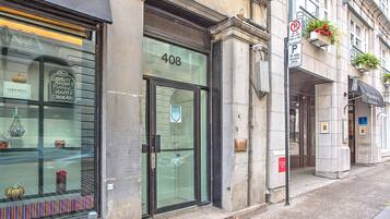 Un edificio con puerta de vidrio marcada con el número 408, una señal de no estacionamiento y una jardinera en la acera.