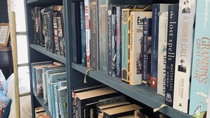 Una estantería llena de libros, algunos con títulos y autores visibles.