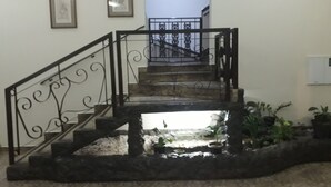 Un escalier orné de rampes en métal ouvragé et de marches en pierre, menant à l’étage supérieur.