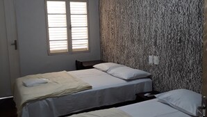 Une chambre d’hôtel avec deux lits, un ventilateur de plafond, un appareil de climatisation et une fenêtre avec des stores.