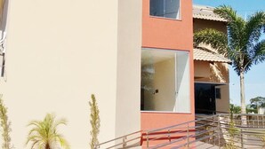 A hotel named 'CASAS NOVAS' with a modern design, featuring a prominent CN logo, a staircase leading to the entrance, and a palm tree in the foreground.