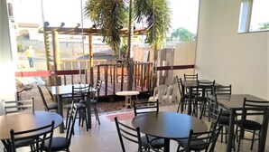 A restaurant with multiple tables and chairs, a covered outdoor seating area, and a view of the street outside.