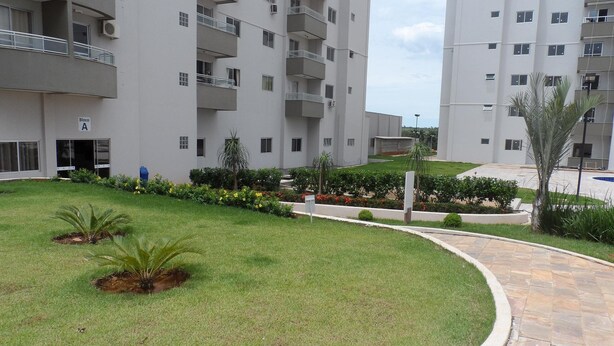 Un immeuble résidentiel doté de nombreux balcons, d’une pelouse bien entretenue et d’un chemin piétonnier dallé.
