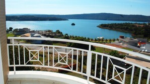 A balcony with a view of a lake, surrounded by buildings and greenery. - Enseada Nautico - JC Temporada (Caldas Novas)