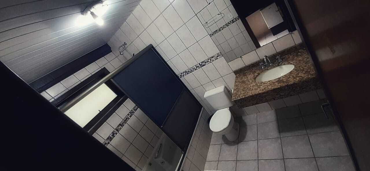 A bathroom with a white toilet, a sink, and a shower area.