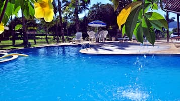 Una piscina al aire libre, sombrillas, sillones reclinables de piscina