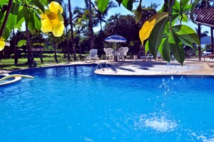 Una piscina al aire libre, sombrillas, sillones reclinables de piscina