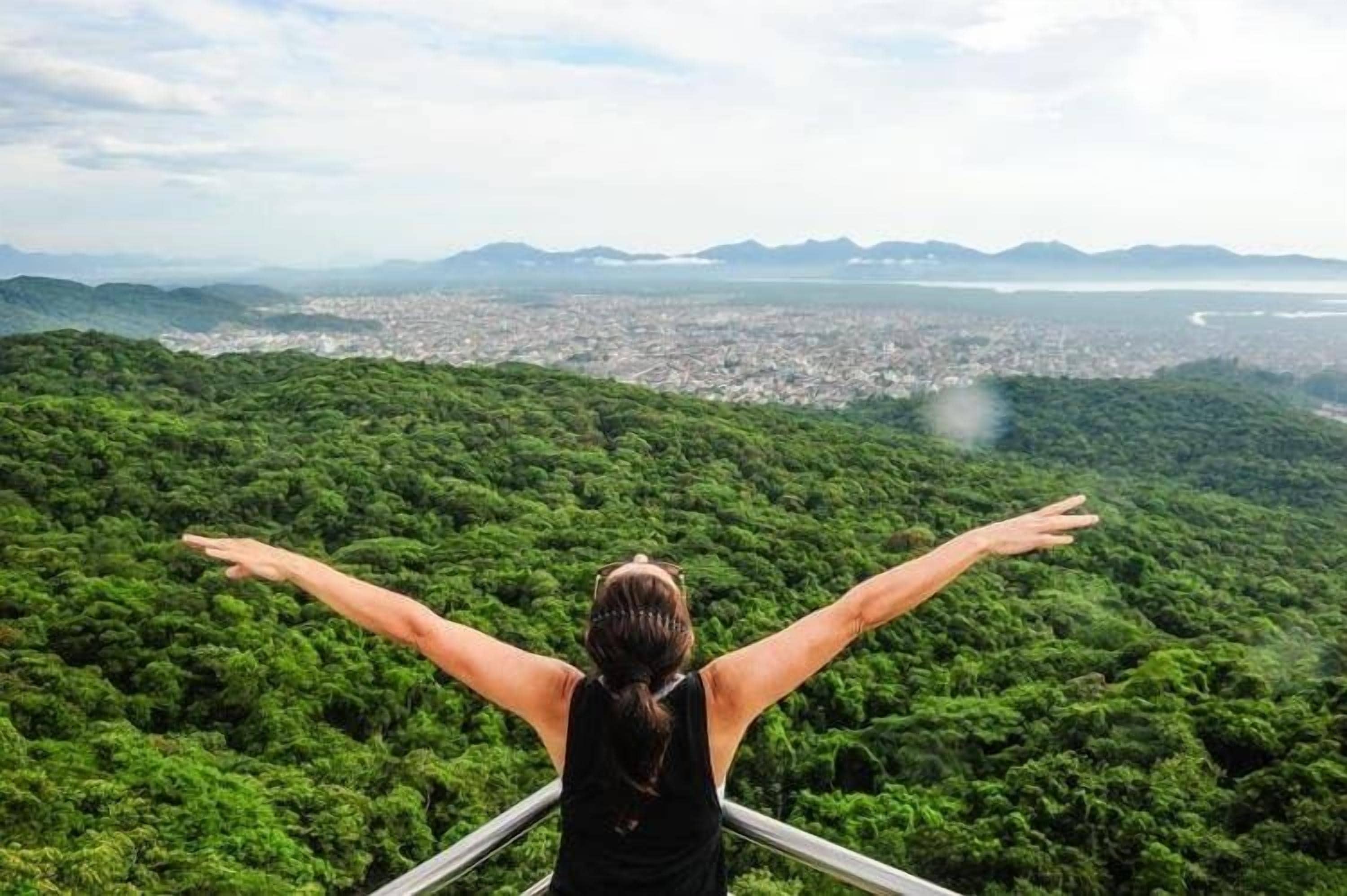 A person with arms outstretched overlooking a city from a high vantage point.